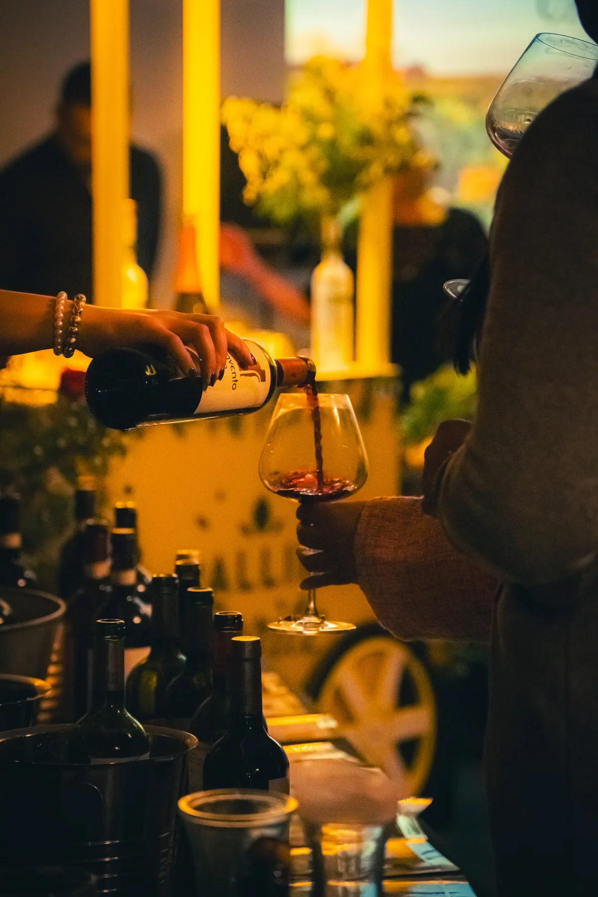 Mesa de degustación con botellas y copas bajo una pérgola iluminada.