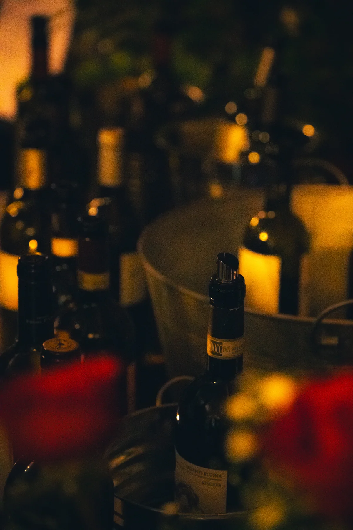 Copas y botellas de vino sobre una mesa en un evento nocturno.