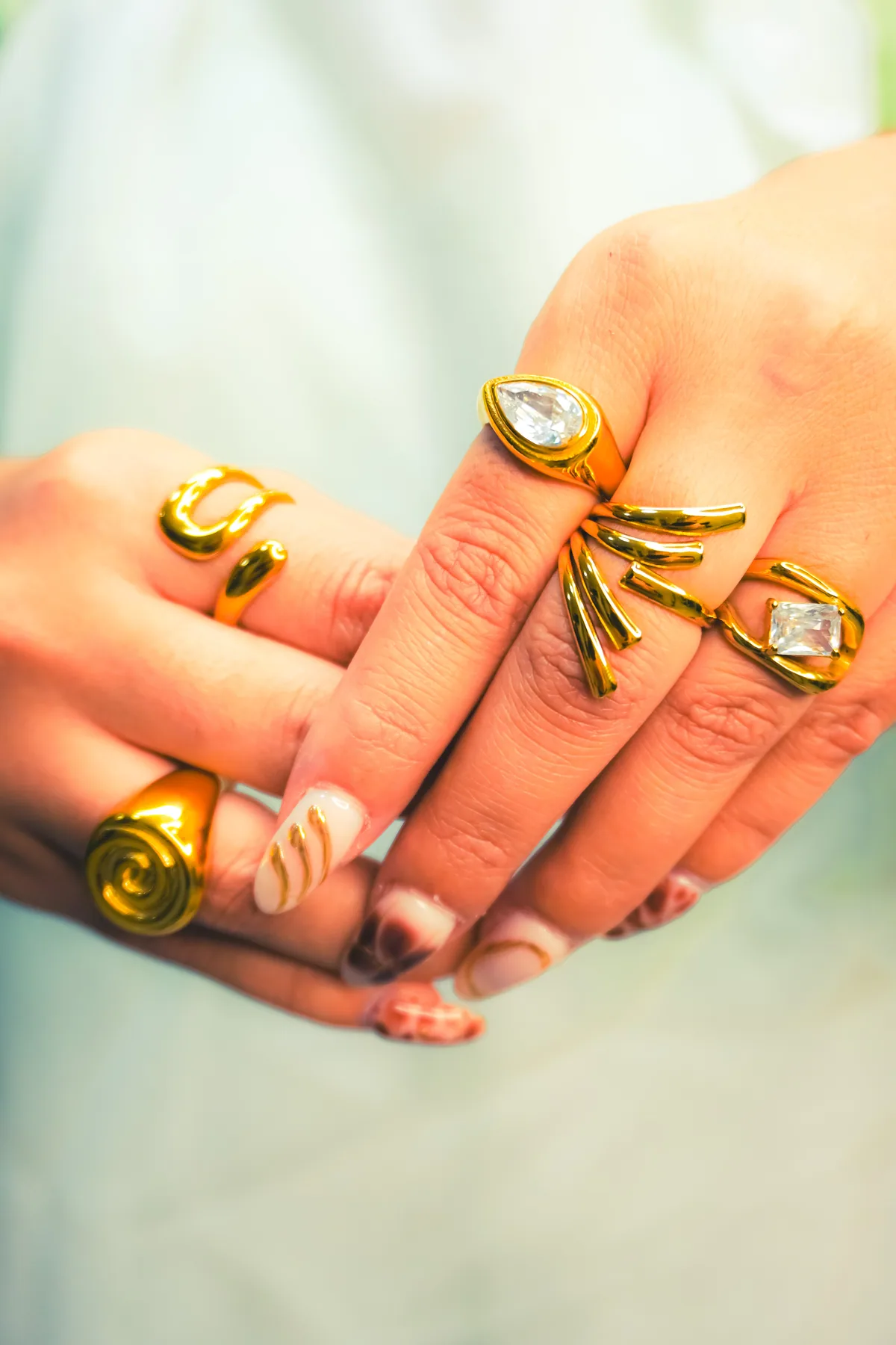 Anillos dorados fotografiados sobre una mano con fondo claro.