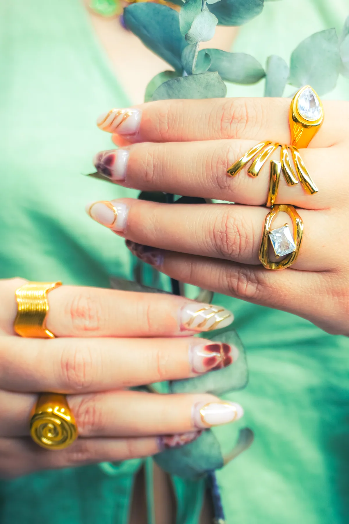 Varios anillos dorados lucidos sobre un fondo verde.