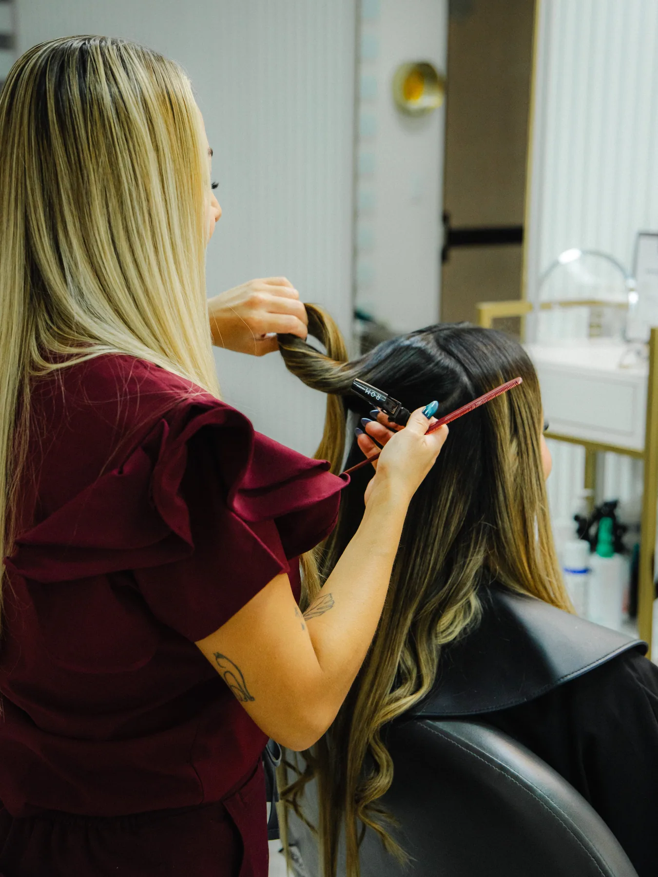 Profesional arregla el cabello de una clienta frente al espejo.