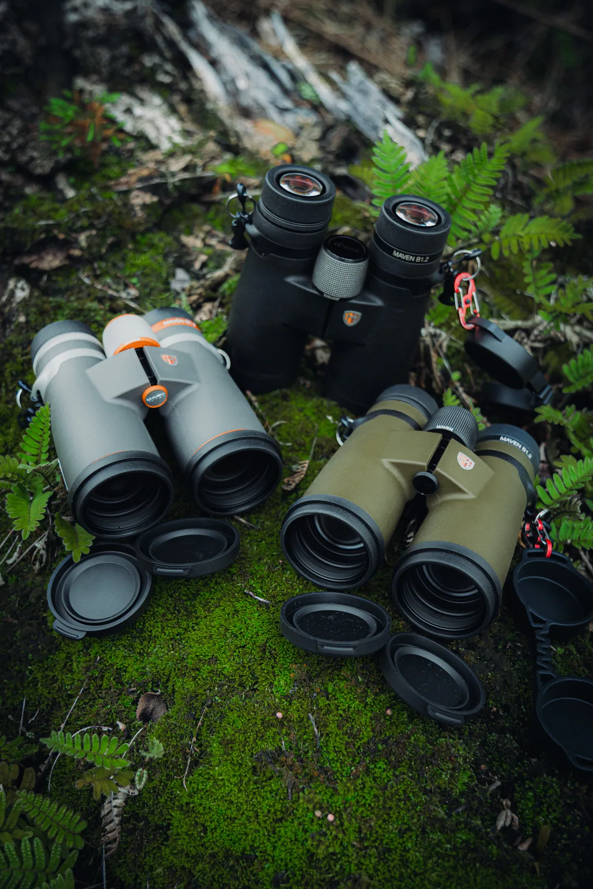 Prismáticos de observación sobre musgo y hojas en el bosque.