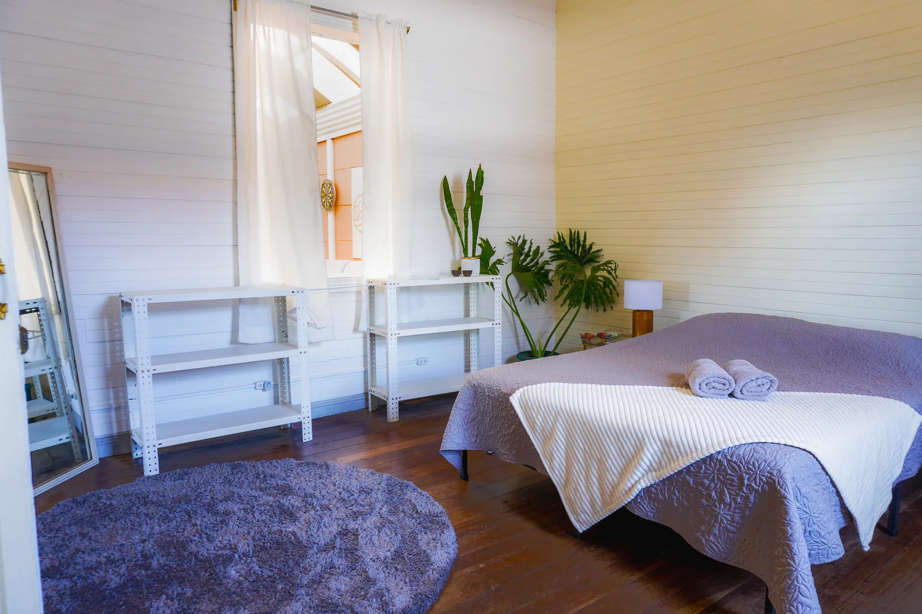 Habitación luminosa con cama, mesa auxiliar y ventana amplia.