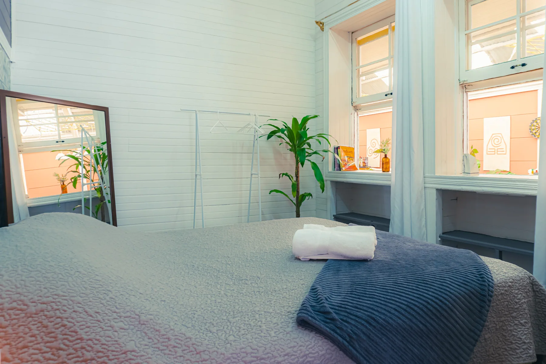 Habitación luminosa con cama y ventanas altas.