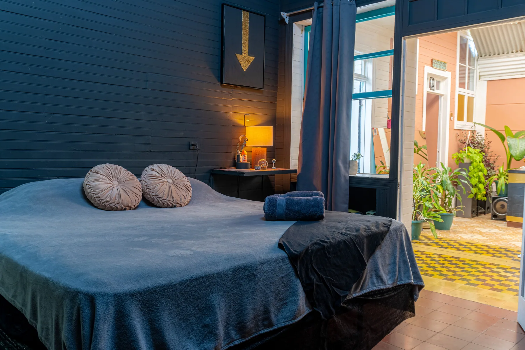 Cama y luces cálidas en una habitación de tonos azules.