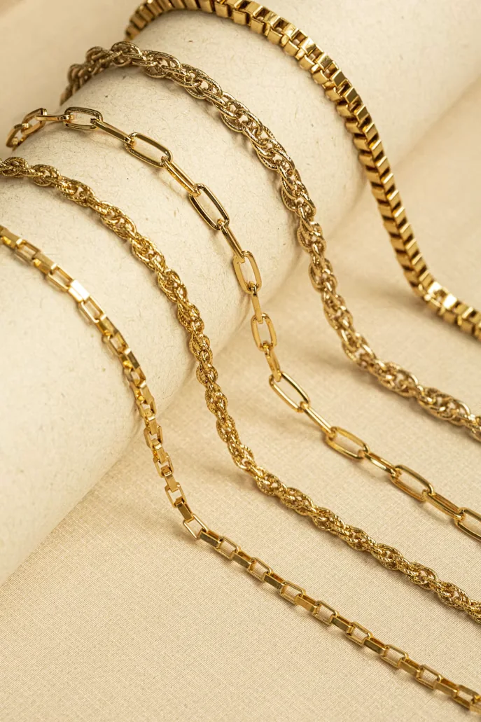 Cadenas y pulseras doradas sobre tela beige