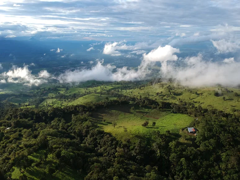 Paisaje de colinas, fincas y bosque de montaña bajo nubes